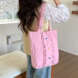 Vue détaillée du dos d'un sac cabas en nylon rose avec volants et boutons colorés