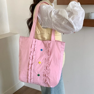 Détail du sac cabas en nylon rose avec volants verticaux et trois boutons colorés décoratifs