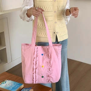 Vue détaillée du cabas en nylon rose avec bords à volants et boutons colorés décoratifs