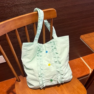 Détail d'un sac en nylon vert clair avec bords à volants et trois boutons décoratifs
