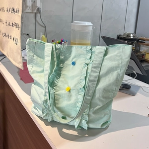 Détail du sac fourre-tout en nylon vert menthe avec bords à volants et boutons colorés
