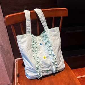 Détail d'un sac cabas en nylon vert clair avec bords volantés et boutons colorés