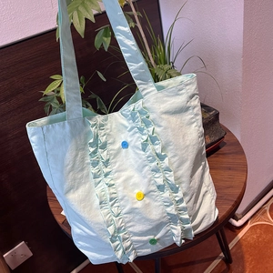 Détail du sac cabas en nylon vert menthe avec bords à volants et boutons en résine