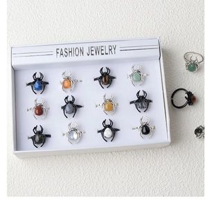 Detailed display of 12 punk spider rings with various gemstone inlays in a white box