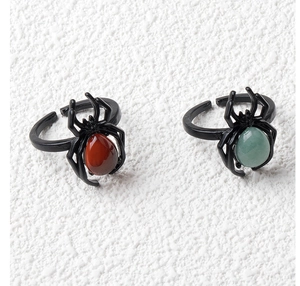 Detailed macro of punk spider rings with red and green gemstone inlay and matte black finish