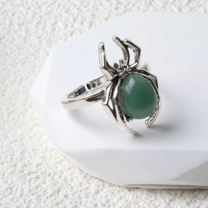 Macro shot of silver spider ring featuring a green teardrop gemstone on white background