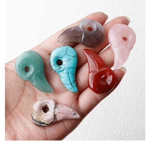 Detailed close-up of natural crystal bird skull charms held in hand to show scale