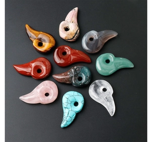 Macro detail of bird skull pendants carved from natural tiger eye and rose quartz stones