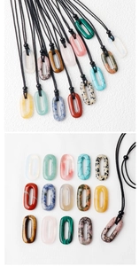 Vue macro de divers pendentifs ovales en pierre naturelle avec cordons noirs sur blanc