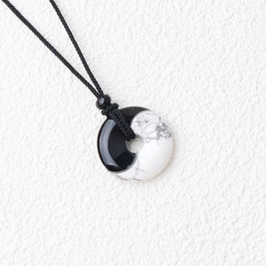Detailed macro view of the Tai Chi Yin Yang pendant showing black obsidian and white stone
