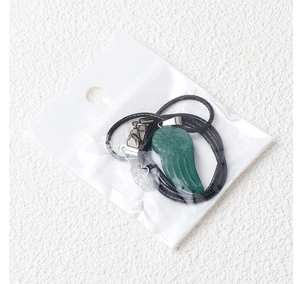 Détail du pendentif ailes d'ange en cristal vert sur une chaîne en cordon noir réglable
