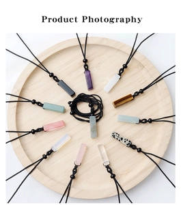 Various rectangular natural crystal pendants on a wooden tray with black woven cords