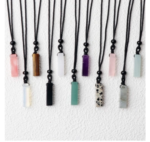 Detailed view of eleven assorted rectangular natural gemstone pendants with black cords