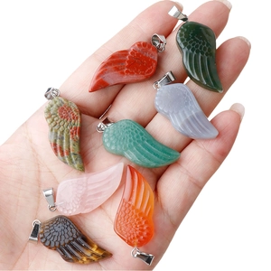 Huit pendentifs ailes d'ange en pierres naturelles diverses tenus dans la main