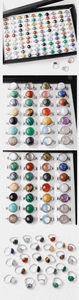 Macro display of 15mm natural stone rings in various colorful crystals on black jewelry tray