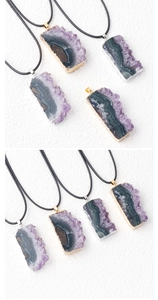 Detailed view of raw purple amethyst slice pendant with gold plated edges on black cord