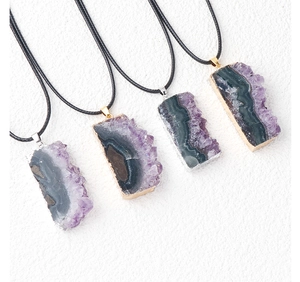 Detail of raw amethyst crystal slice pendants with gold and silver plated edges
