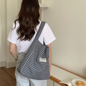 Detailed view of the blue checkered tote bag showing the side label and thick canvas fabric