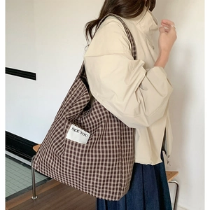 Detail of plaid canvas tote bag with See You label and shoulder strap for commute