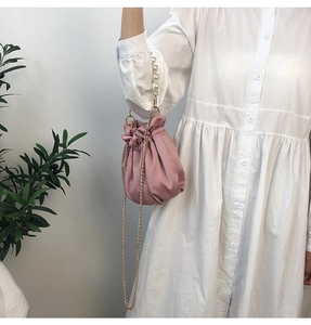 Detailed close-up of pink pleated satin dumpling bag with elegant white pearl handle
