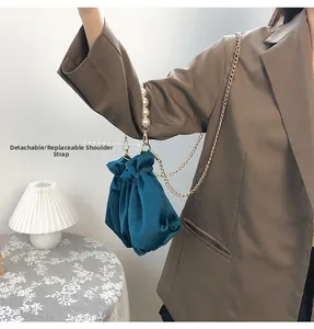 Blue satin cloud bag with pearl handle and detachable gold chain strap shown on shoulder