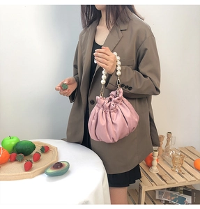 Detail of pink pleated cloud bag featuring large pearl handle on a female model