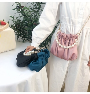 Detailed shot of three satin cloud bags with pearl handles and gold chain straps