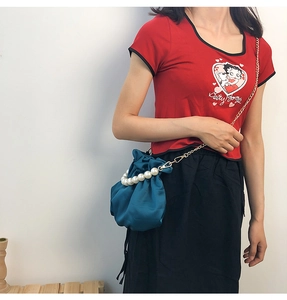 Detailed view of peacock blue satin bucket bag with pearl handle and chain strap