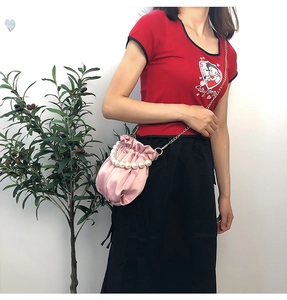 Pink satin pleated cloud bag detail with pearl handle and gold chain on model