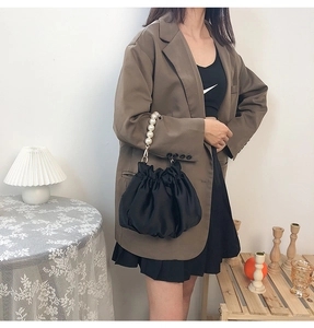 Detail of black satin cloud bag featuring large pearl handle and pleated drawstring closure