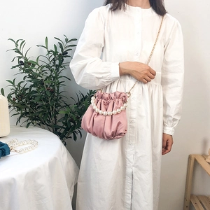 Pink satin pleated cloud bag with large pearl handle and gold chain strap on model