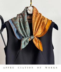 Detail of teal and orange paisley silk scarf paired with a black top and camellia brooch