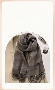 Detail of winter thick plaid scarf with tassels and houndstooth texture in brown