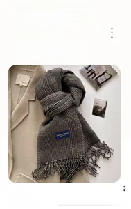 Detailed view of checkered scarf with fringe trim and Elegant & Classic woven label