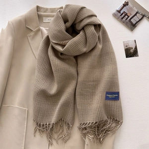 Detailed view of beige plaid scarf with waffle texture and handmade fringed tassels