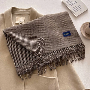 Close-up of thick checkered scarf with tassels on beige wool coat with a cozy coffee scene