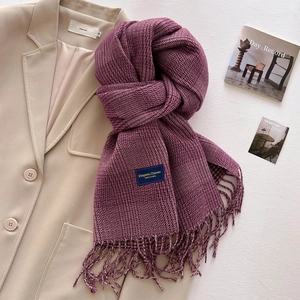 Detailed texture of thick purple and beige plaid scarf with fringes on beige blazer