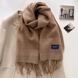 Brown plaid cashmere scarf with tassel edges on a beige blazer, elegant autumn winter style