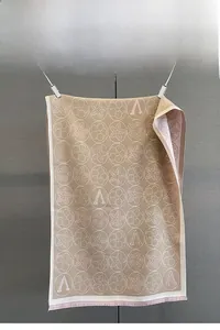 Détail du motif jacquard à fleurs et lettre A sur écharpe d'hiver kaki avec franges