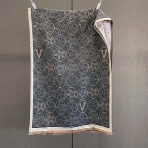 Détail de l'écharpe en jacquard gris foncé avec motifs floraux, lettres V et des franges
