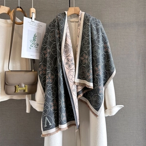 Détail d'une écharpe pashmina grise à fleurs avec franges sur manteau de laine