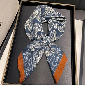 Detail of navy blue paisley silk twilly with sun motifs and contrast orange hem