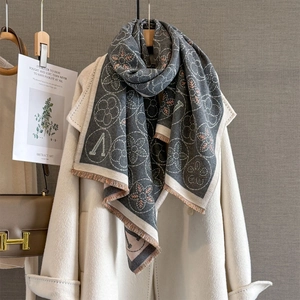 Gros plan sur le motif jacquard floral et les fines franges de l'écharpe grise