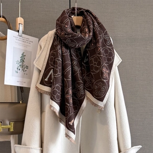 Détail macro d'une écharpe marron foncé avec motifs jacquard fleuris et bords à franges