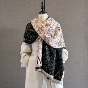 Détail du tissage jacquard floral et lettre V sur l'écharpe en cachemire noir et beige