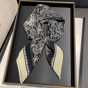 Classic vintage paisley print silk scarf in black and white shown on a display tray