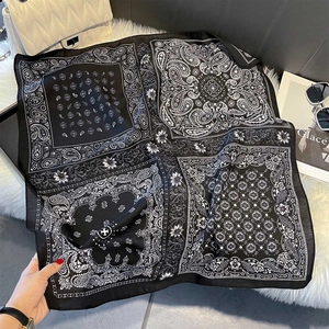 Détail d'un foulard carré en soie à motif Paisley noir et blanc sur fond en peluche blanc