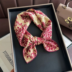 Baroque red and beige silk scarf styled as a bow on a black display tray with accessories