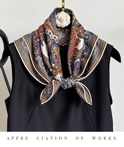 Detailed view of the paisley silk-wool blend scarf draped over a black dress with camellia