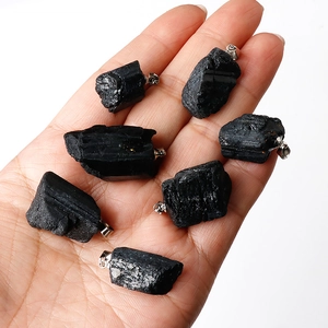 Natural black tourmaline raw stone pendants held in hand with silver metal clasp
